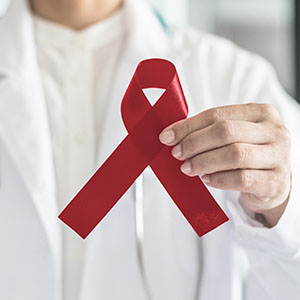 A healthcare professional holds a red ribbon